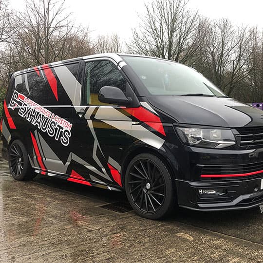 Digitally printed full vehicle wrap on a black van with red and black graphics